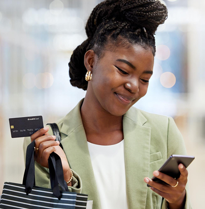 African descent lady all smiles holding her card in one hand and phone in the other | Naivas online shopping in Kenya