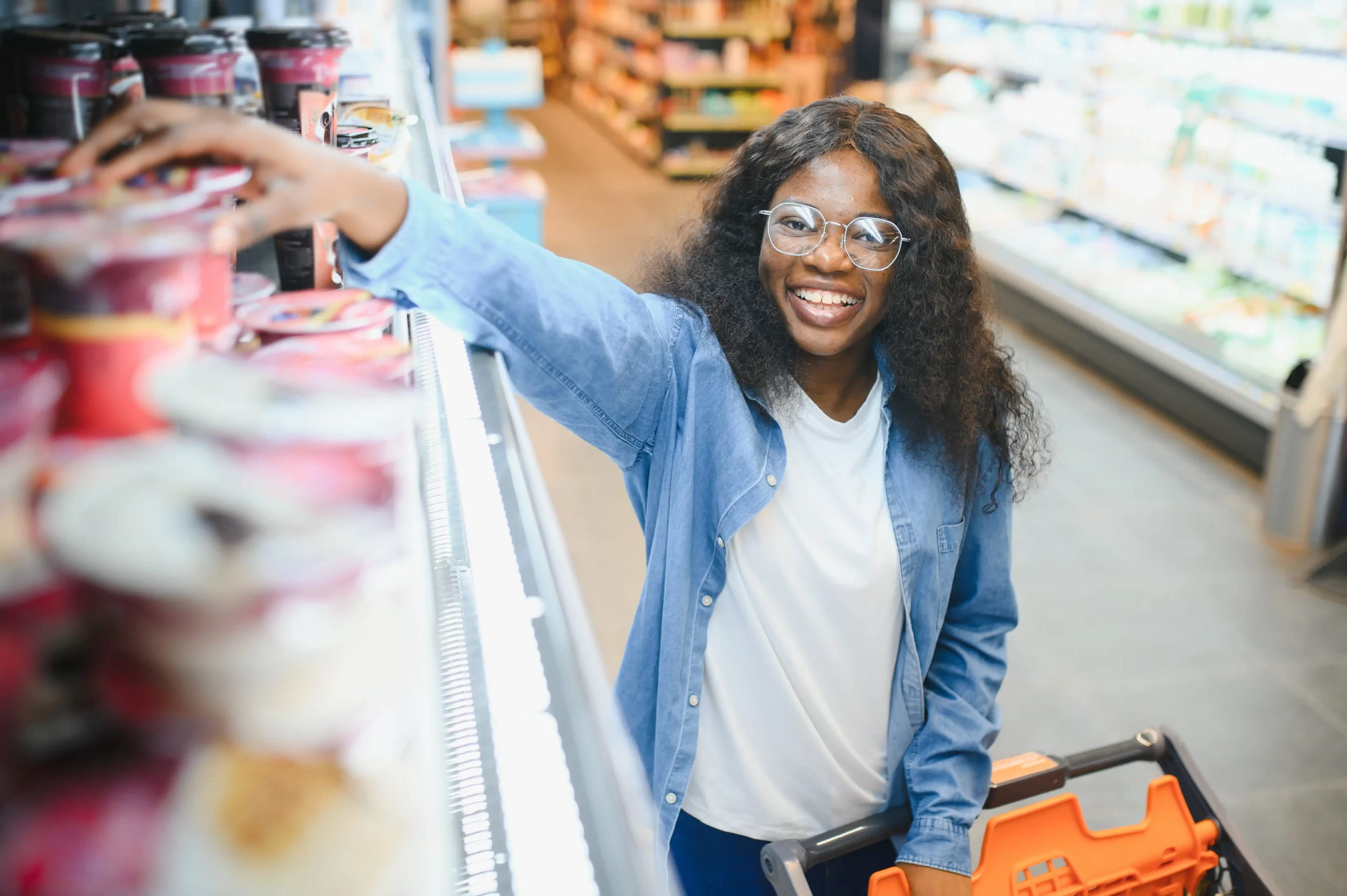 African descent girl all smiles picking yoghurt from the shelves while holding her trolley in Naivas | online shopping in kenya